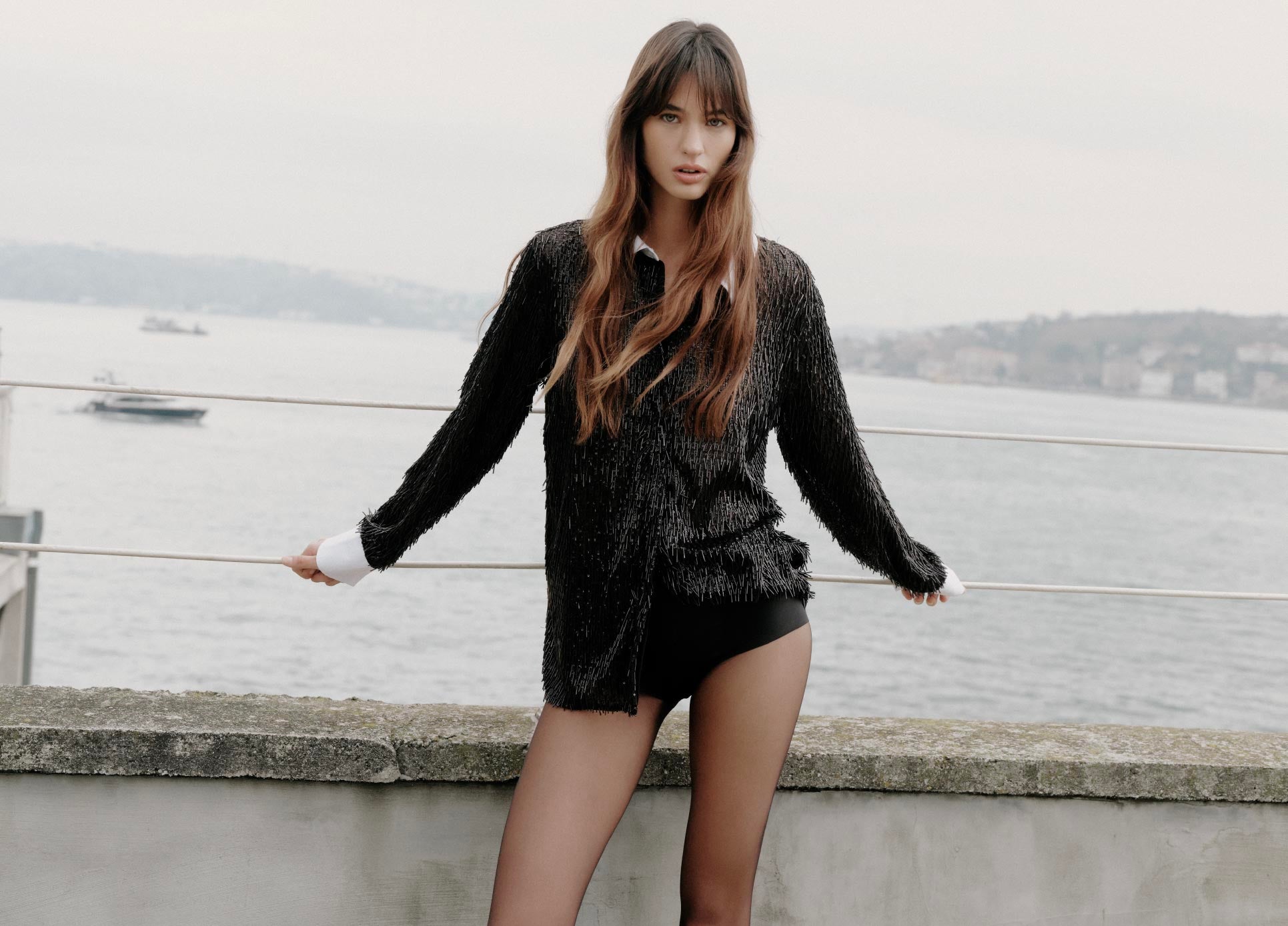 Woman in a black sequin outfit standing by a waterfront